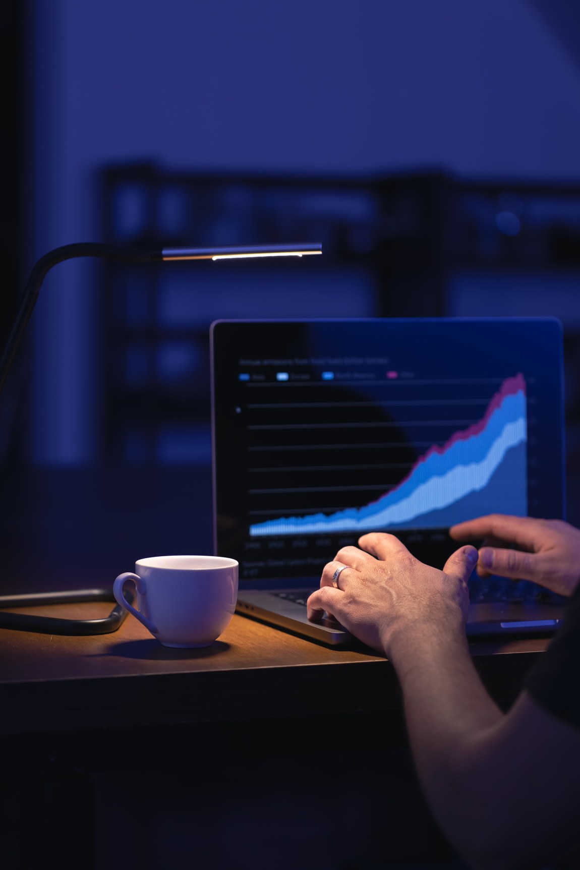 Laptop mit Börsenchart und Kaffeetasse auf einem Schreibtisch am Abend